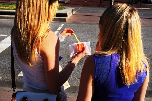 two girls eating mcdonalds fries street photography, colorful, by Manuel Armenis