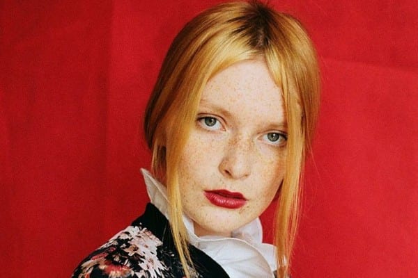 Color portrait of woman in flower top with red background by Oliwia Czarniecka