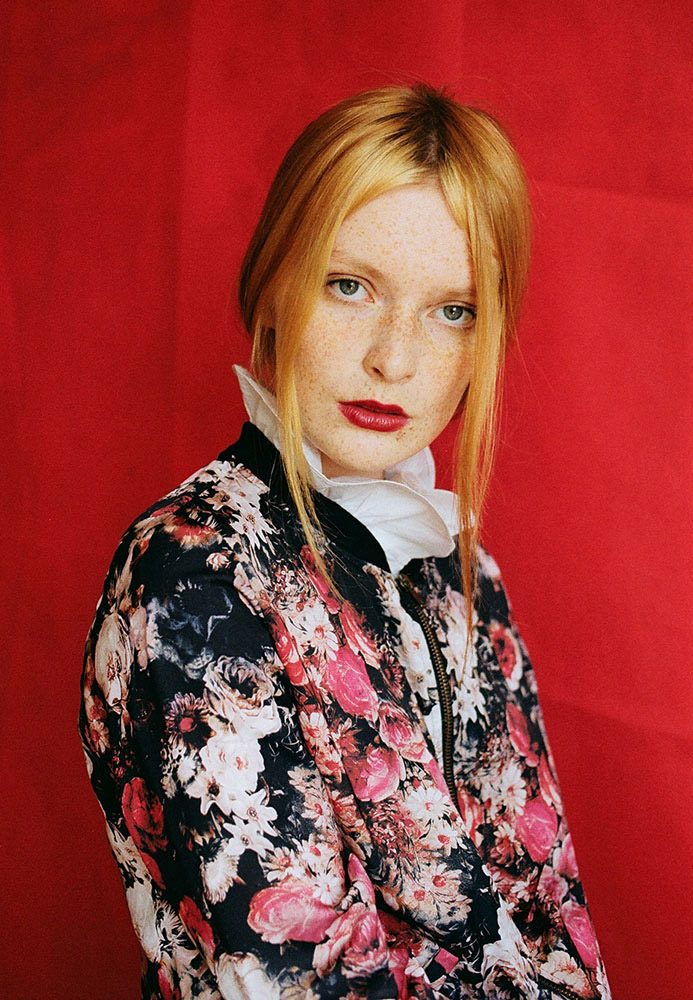 Color portrait of woman in flower top with red background by Oliwia Czarniecka