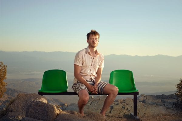 man sitting on a green bench, color portrait photography by dylan collard