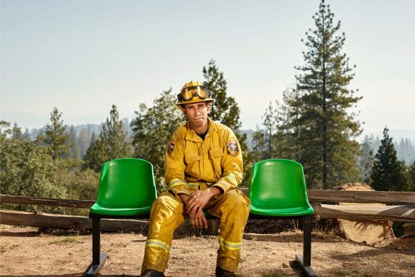 fireman sitting on a green bench, color portrait photography by dylan collard