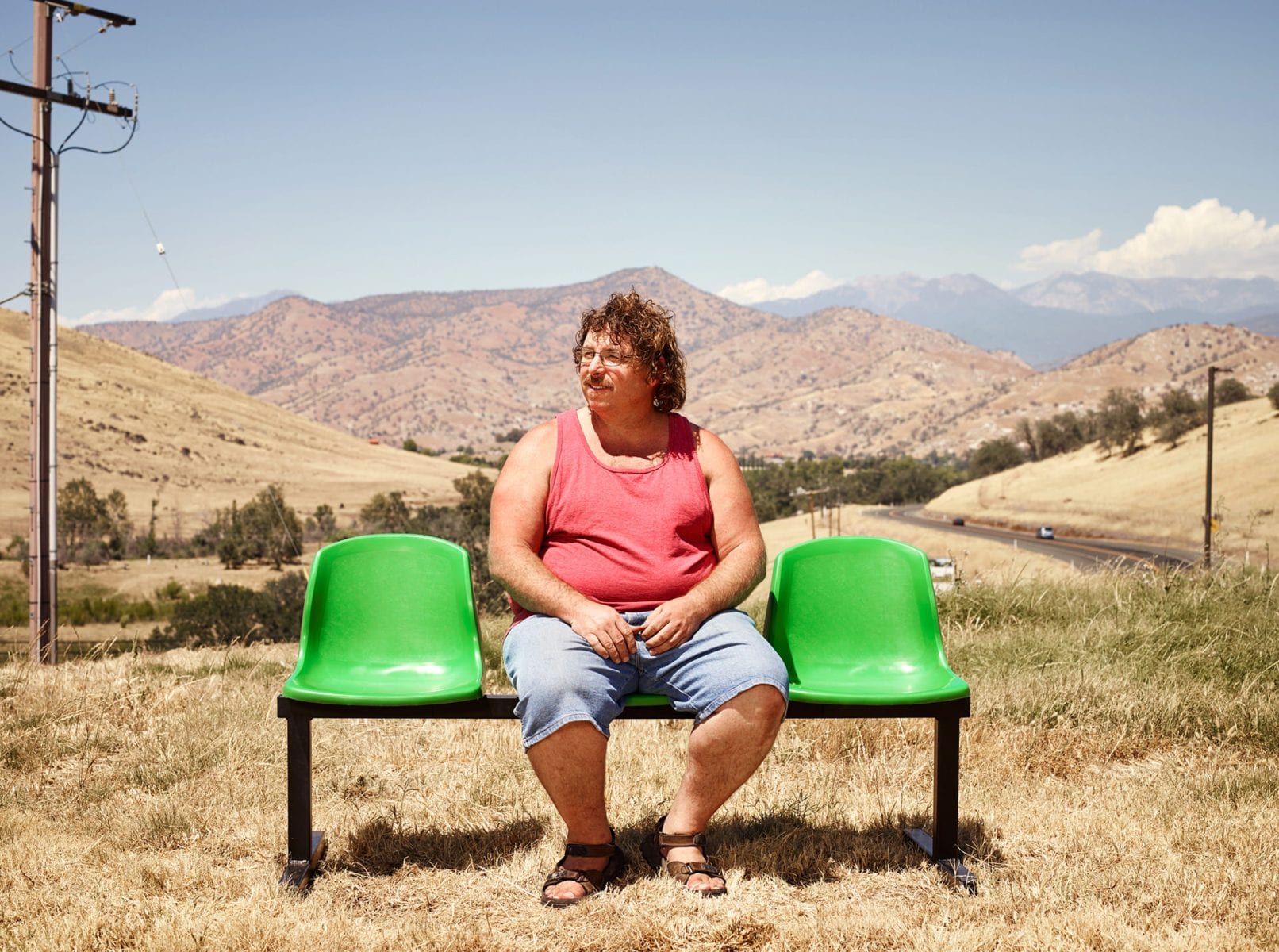 man sitting on a green bench, color portrait photography by dylan collard