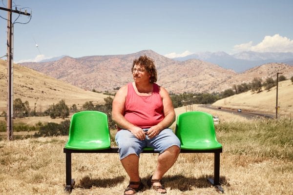 man sitting on a green bench, color portrait photography by dylan collard