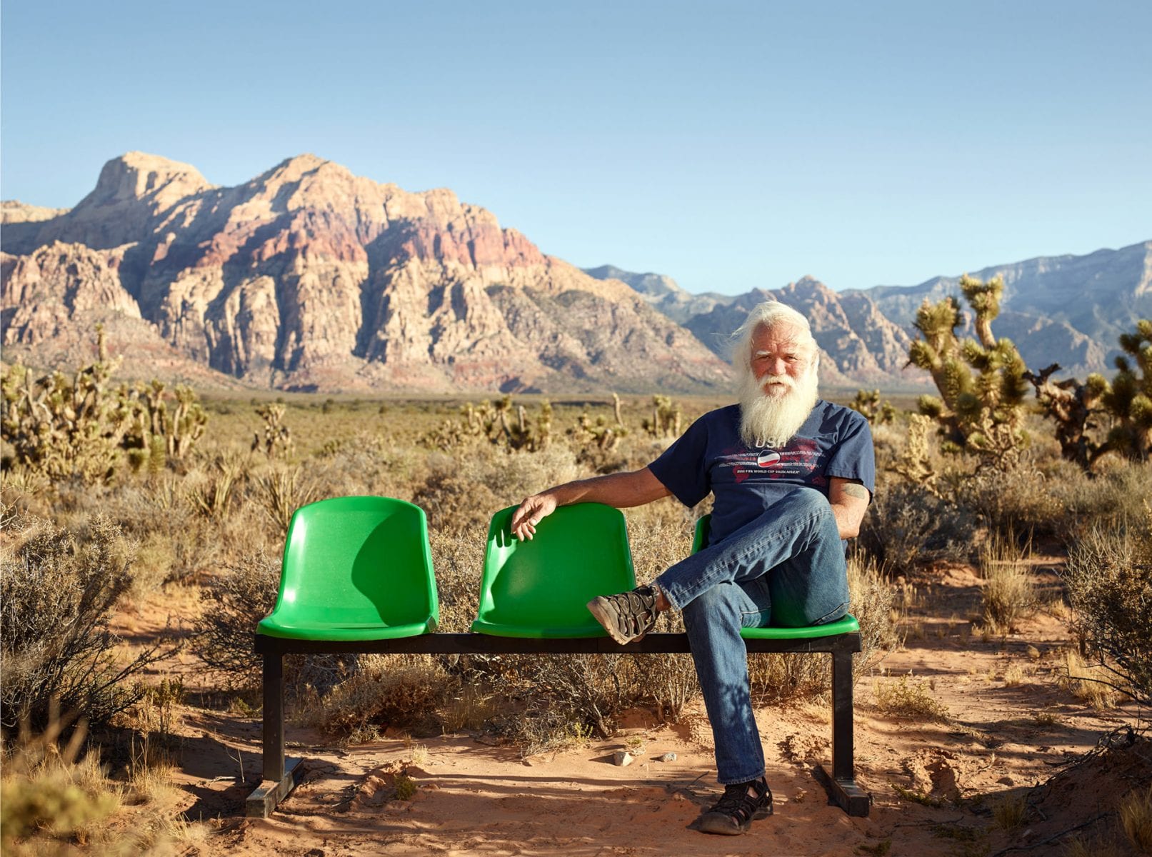 bearded man sitting on a green bench, color portrait photography by dylan collard