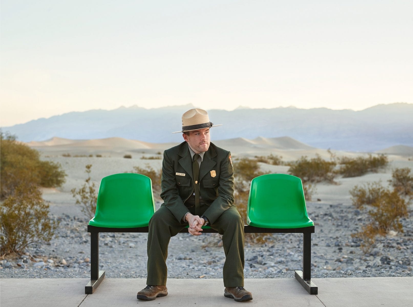 man wearing a hat and sitting on a green bench, color portrait photography by dylan collard