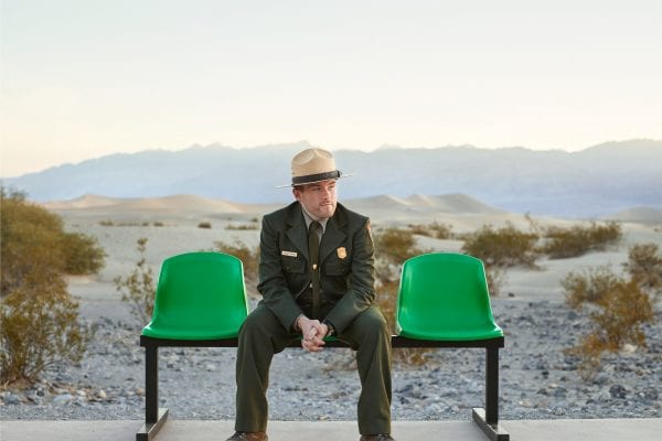 man wearing a hat and sitting on a green bench, color portrait photography by dylan collard