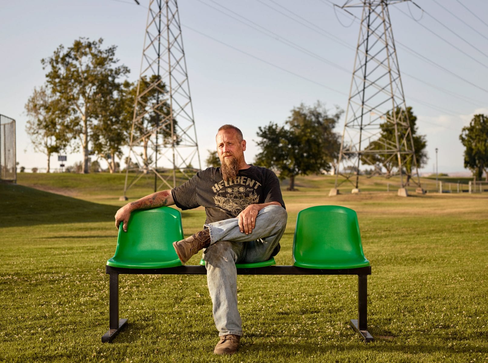 man sitting on a green bench, color portrait photography by dylan collard