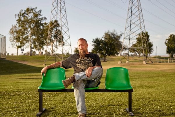 man sitting on a green bench, color portrait photography by dylan collard