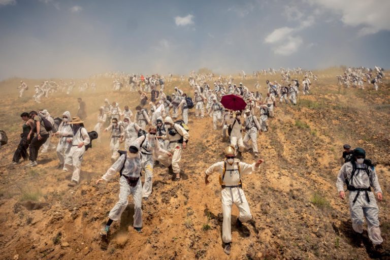 Color photograph of climate activists running into an open coal mine in Germany by David Klammer - People & Photography