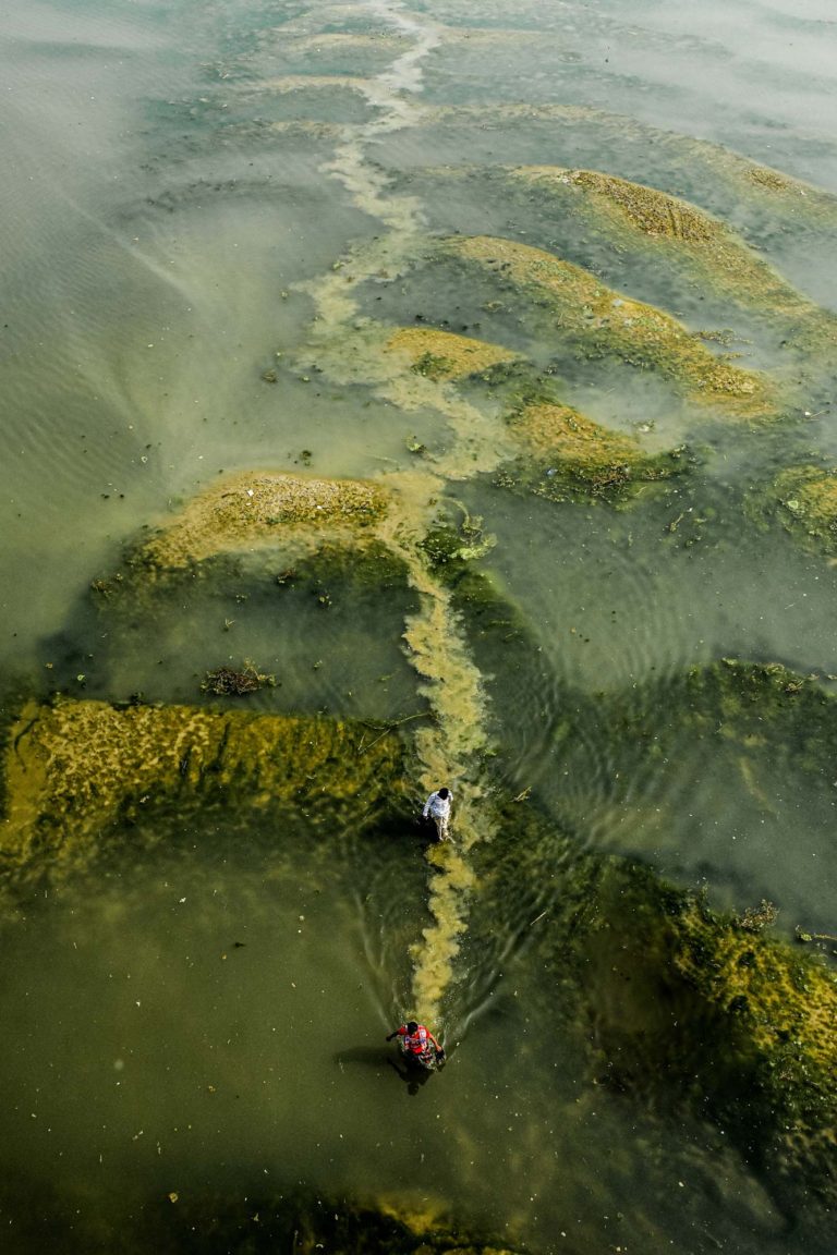 color travel photo of men walking in river in Bangladesh by Rifat Hasan