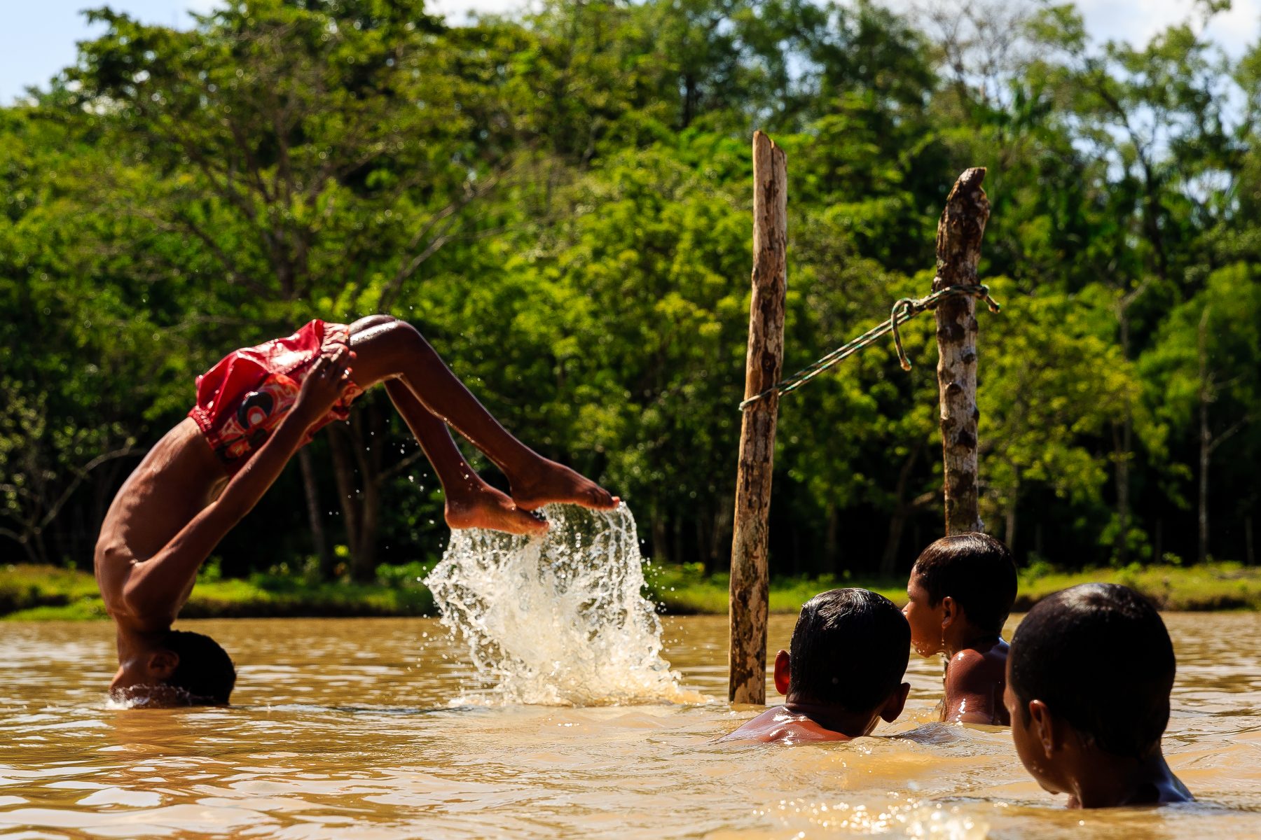 Color photo by Diego Baravelli of boys swimming in a river, Brazil