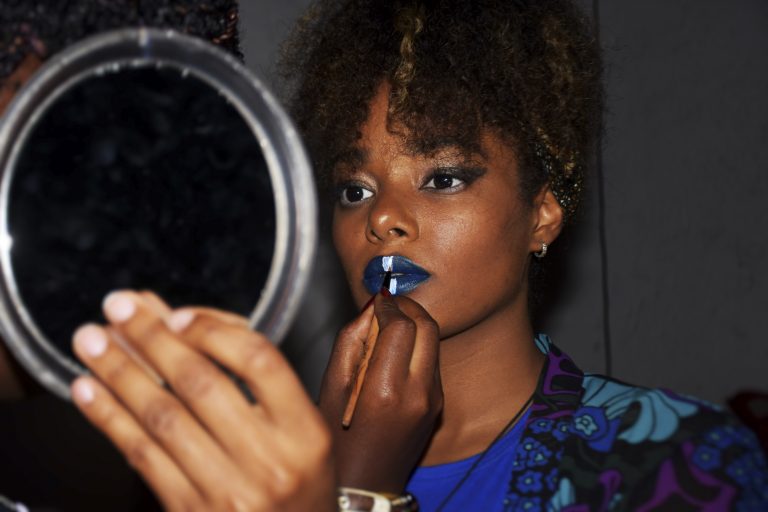 Color photo by Ley Uwera of women applying make up at Goma fashion week, Democratic Republic of the Congo