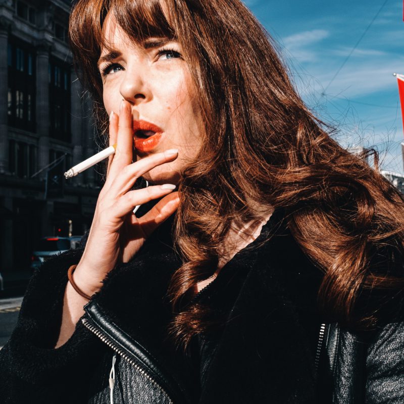 Portrait photograph of a woman with red lipstick and blue eyes in Oxford Street, London, UK by Francesco Gioia