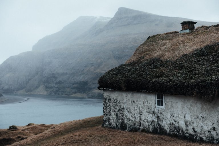 Hannes Becker landscape photo. Grass-roofed house, mountains, Faroe Islands.