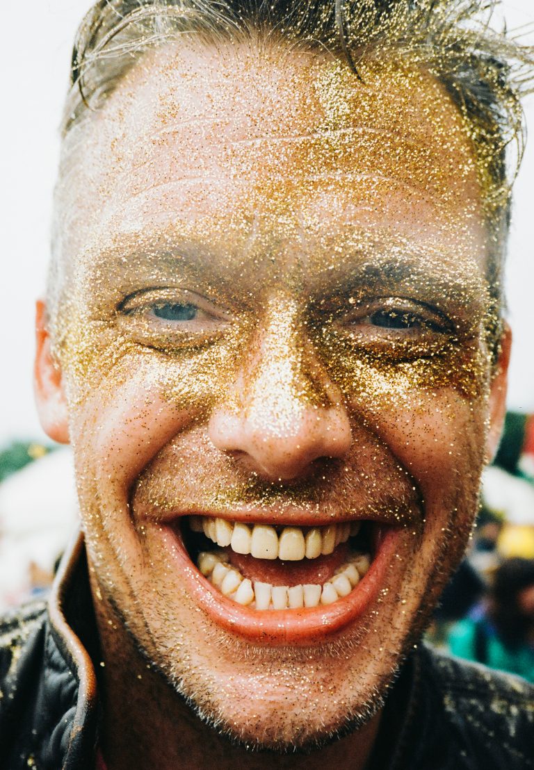 Color portrait by James Marcus Haney, music fan with gold glitter on his face at a music festival