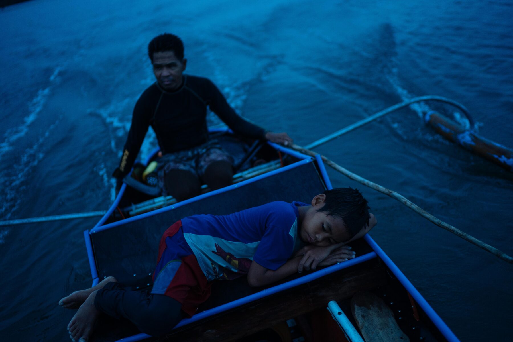 Zaijan Villaruel is seen resting at dusk after fishing with his father Norberto in Bataan, Philippines. Documentary photography by Hannah Reyes Morales. From the series, 'Living Lullabies'