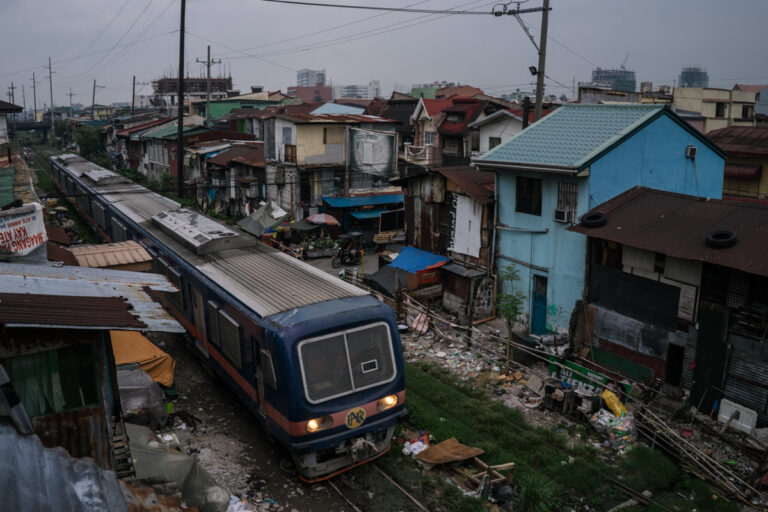 From the series, 'Season of Darkness' by Hannah Reyes Morales. Train going through city slums in the Philippines.