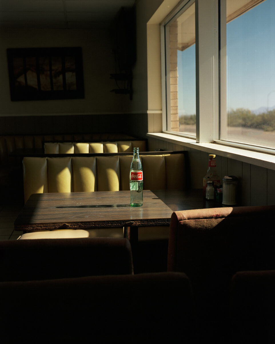 Color photography by Arnaud Montagard. Diner table, empty Coke bottle, from The Road Not Taken