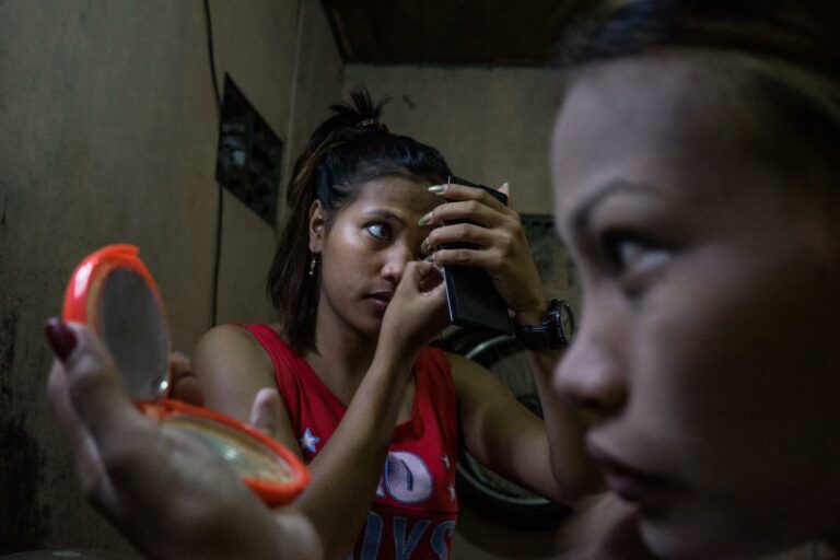 Documentary photography by Hannah Reyes Morales, From the series, 'Shelter from the Storm'. two sex workers apply make up. The Philippines