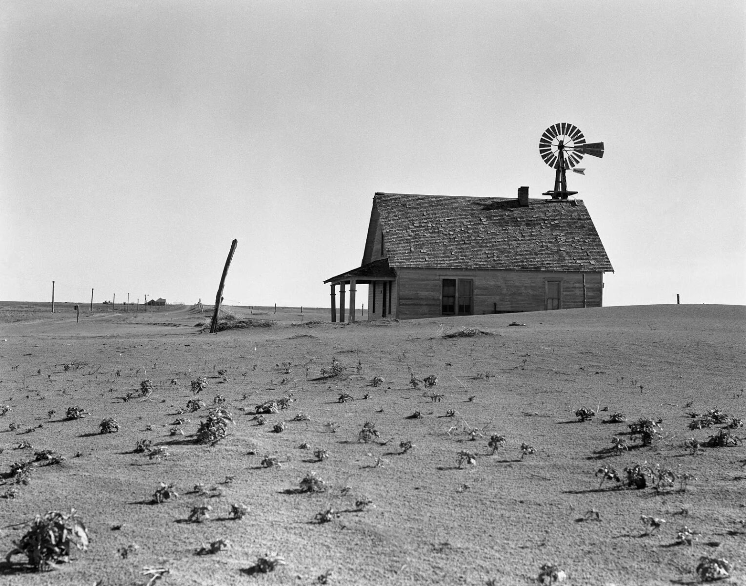 Black and white documentary photography by Dorothea Lange. Dust Bowl farm. Coldwater District, north of Dalhart, Texas. This house is occupied; most of the houses in this district have been abandoned, 1938