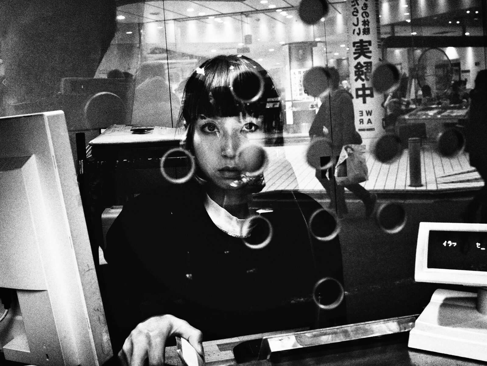 Black and white street photography by Tatsuo Suzuki. Ticket seller, woman, portrait, Tokyo Japan