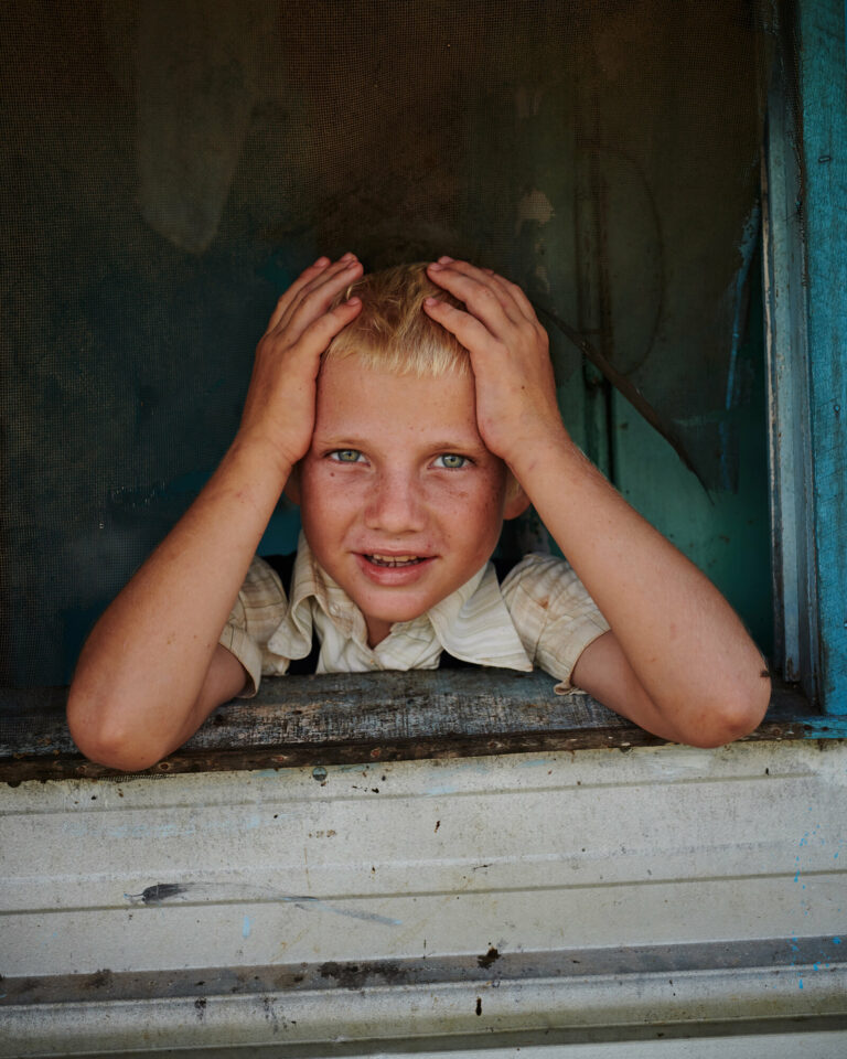 Color film photo by Jake Michaels, portrait of Mennonite boy Belize from the book c.1950