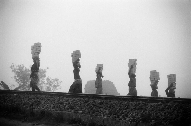 Black and white photography by Pierrot Men, women carrying bricks in Madagascar