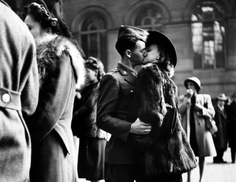 Couple in Penn Station sharing farewell kiss before he ships off to war during WWII, NY, 1943. Black and white photography by Alfred Eisenstadt