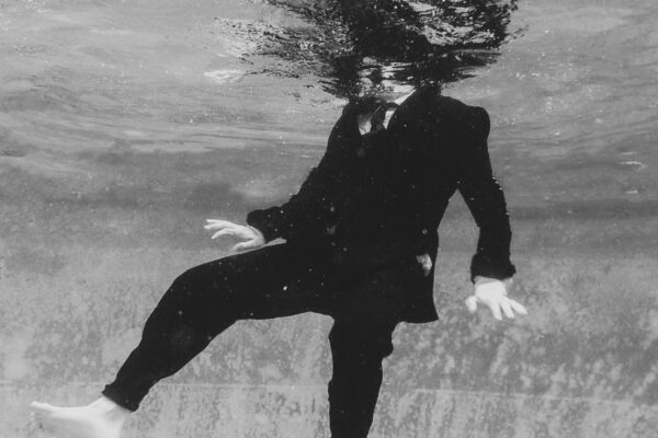 black and white abstract fine art photo of a man in suit under water by Caitie Yevoli