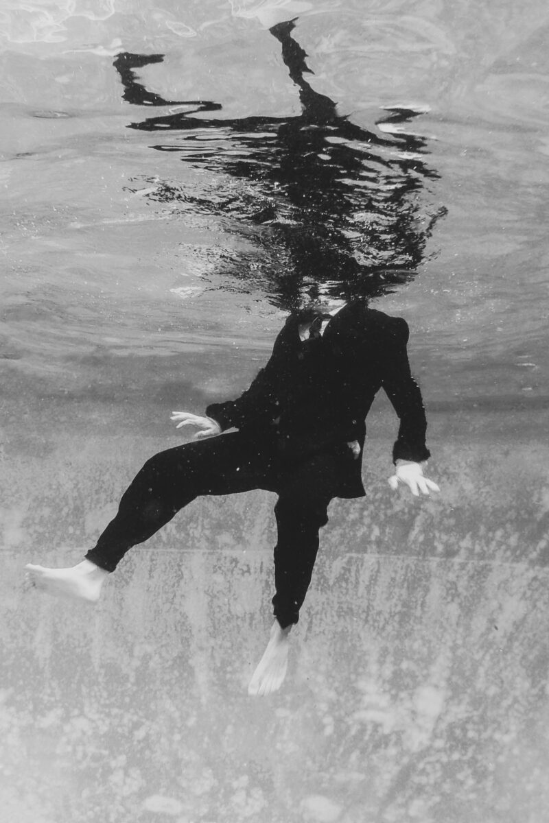 black and white abstract fine art photo of a man in suit under water by Caitie Yevoli