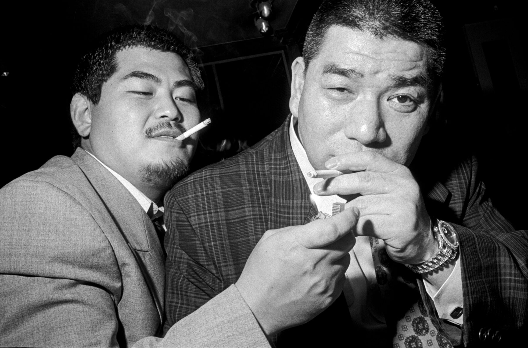 Black and white street photography portrait by Bruce Gilden, two men smoking, Japan