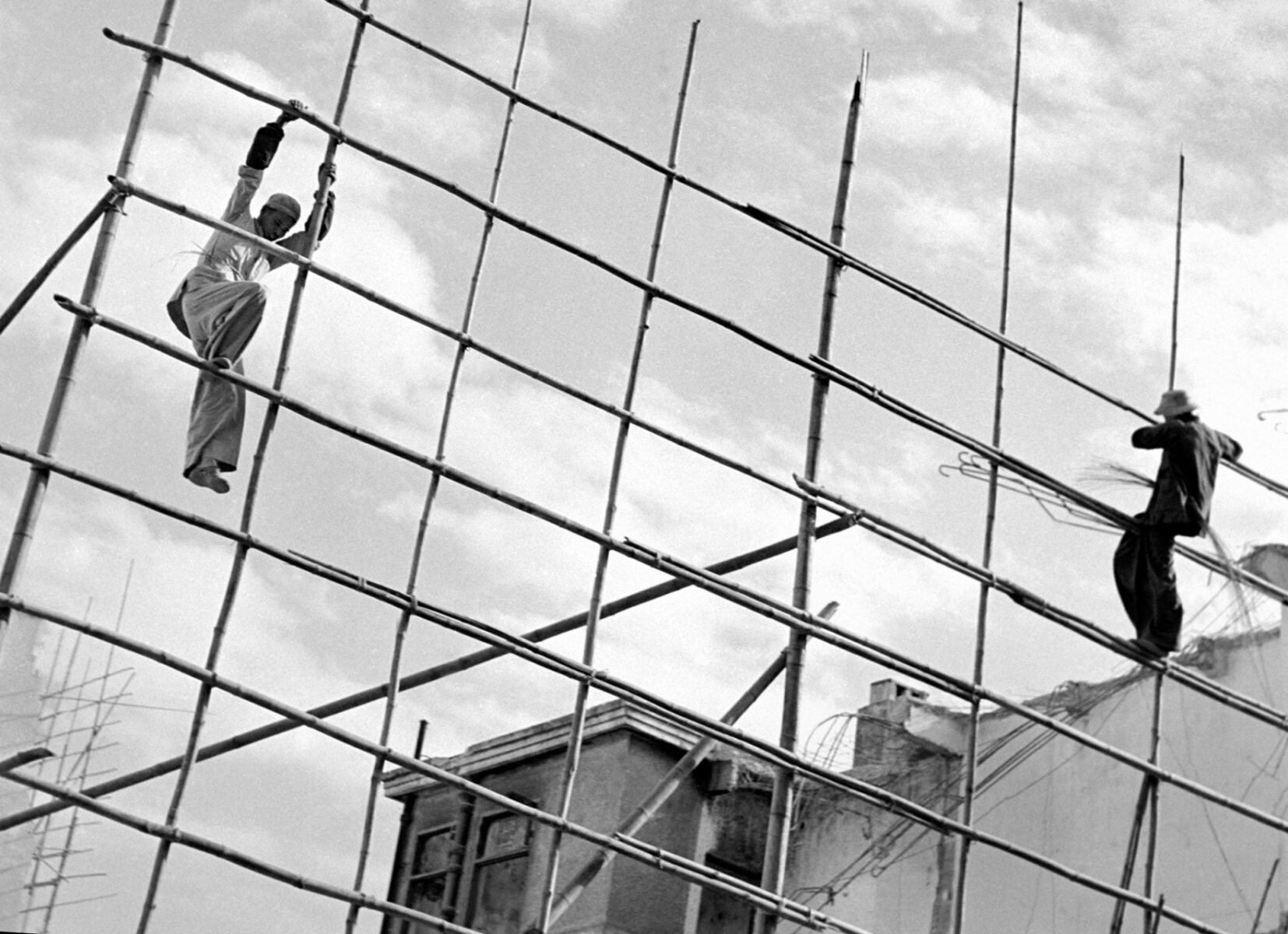 Black & white street photography by Fan Ho. Men on bamboo scaffolding, Hong Kong, 1956