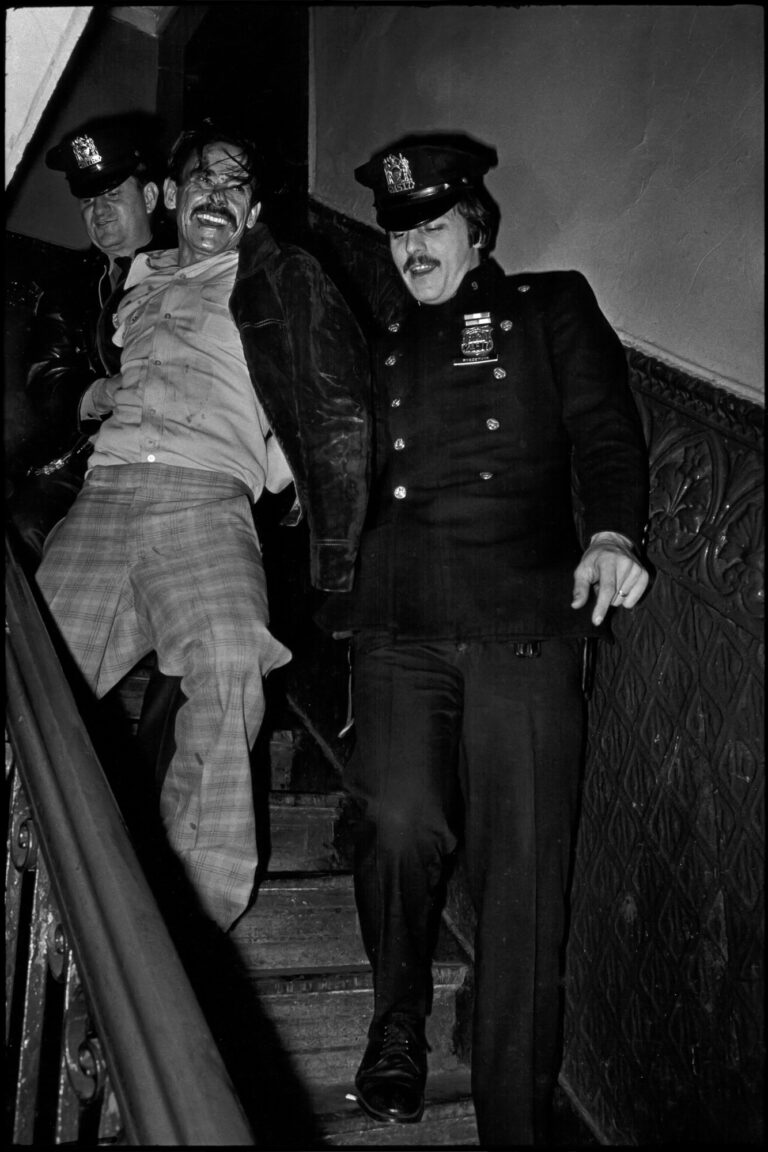 Cops taking disheveled perp downStairs NYC, street photography by Jill Freedman from 'Street Cops'