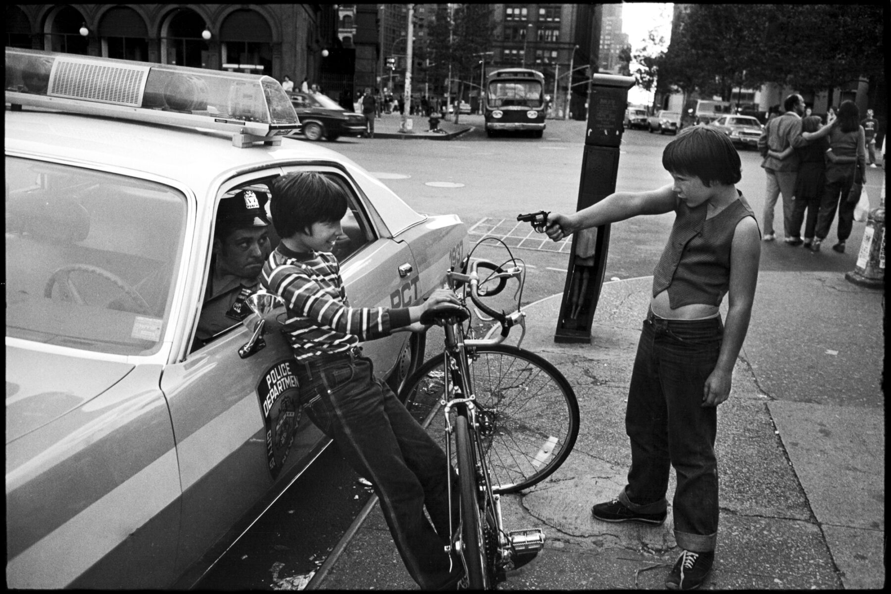 Kids fooling around with toy gun. NYC, street photography by Jill Freedman. From 'Street Cops'