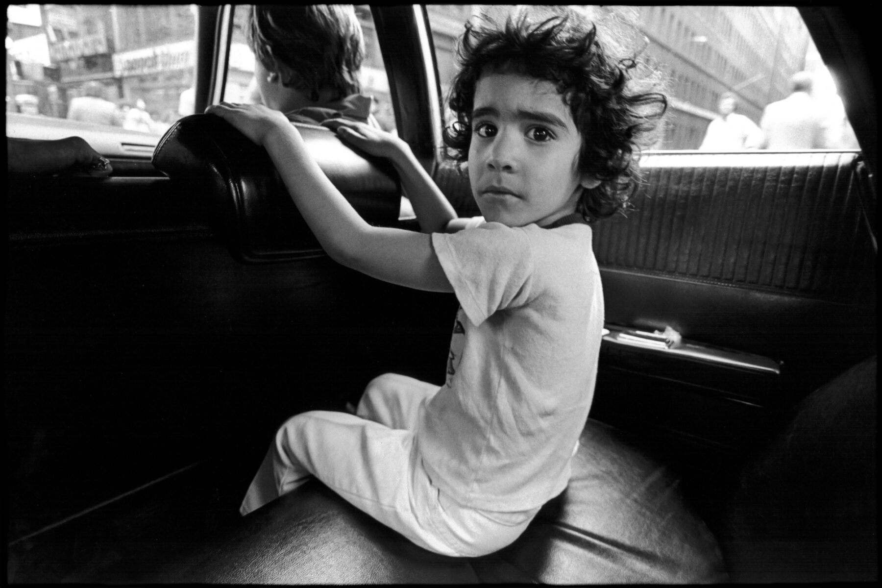 Young boy in the back of a car, street, documentary photography by Jill Freedman from 'Street Cops'