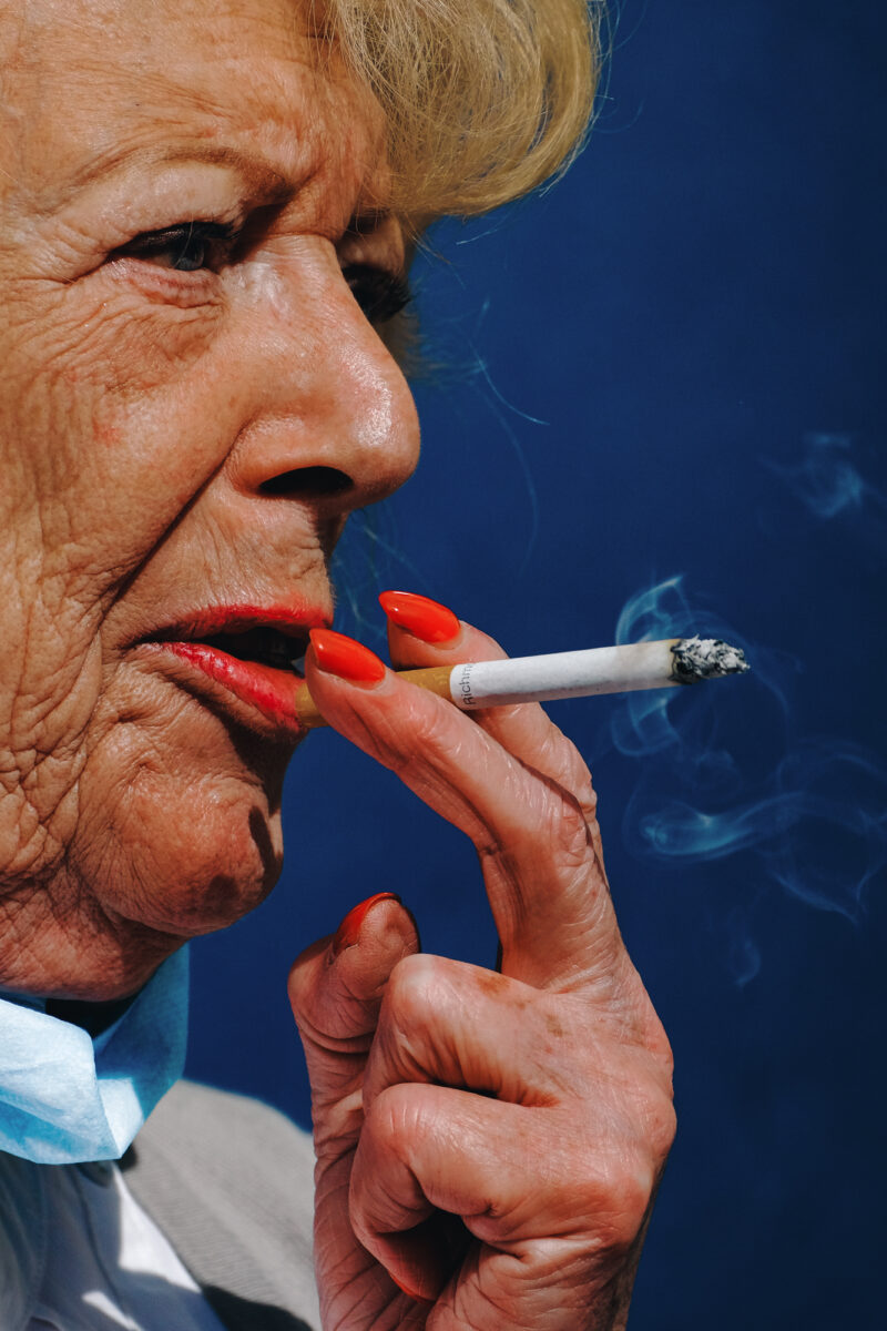 color street photo portrait of a a woman smoking in Leicester Square, London, UK by Francesco Gioia