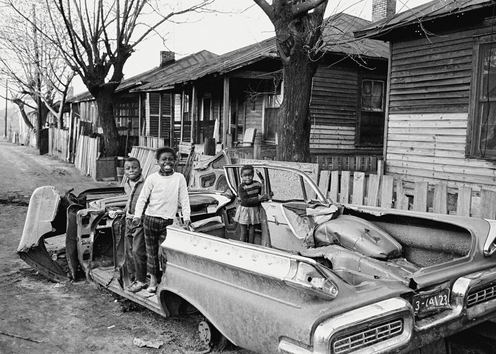 Black & white photography by Thomas Hoepker, Children playing in a car wreck in a black settlment in the Mississippi Delta