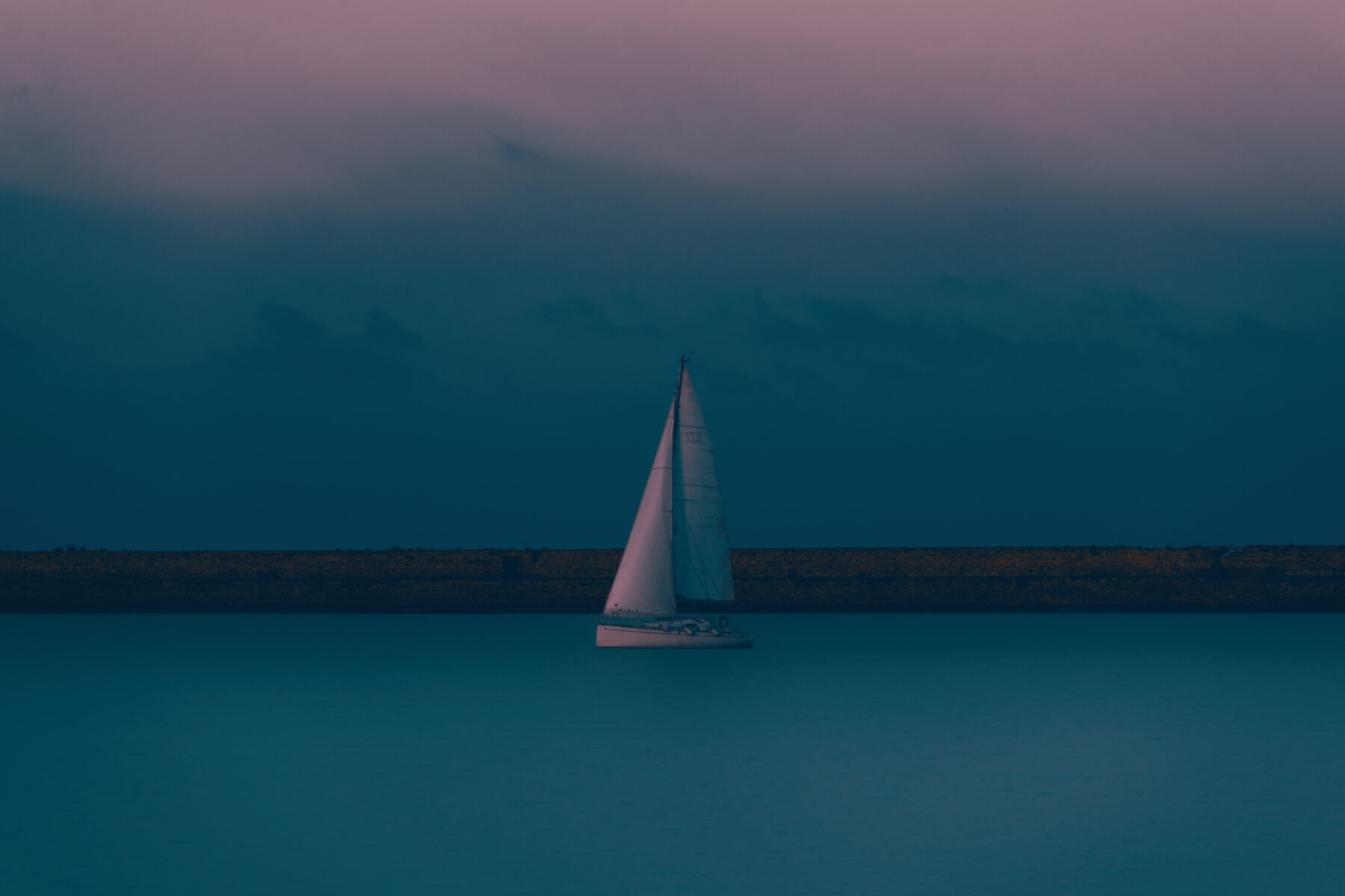 color photo of of a boat and sea line with pink sky and blue water by Christian Bruni