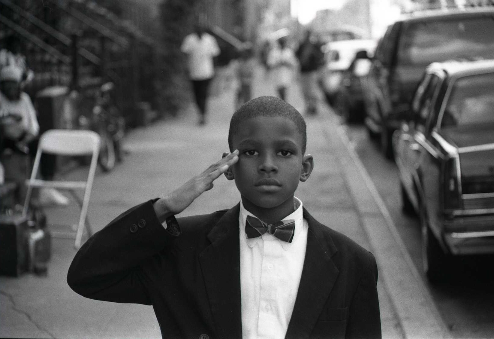 Black and white street photography portrait by Jamel Shabazz. Boy saluting.