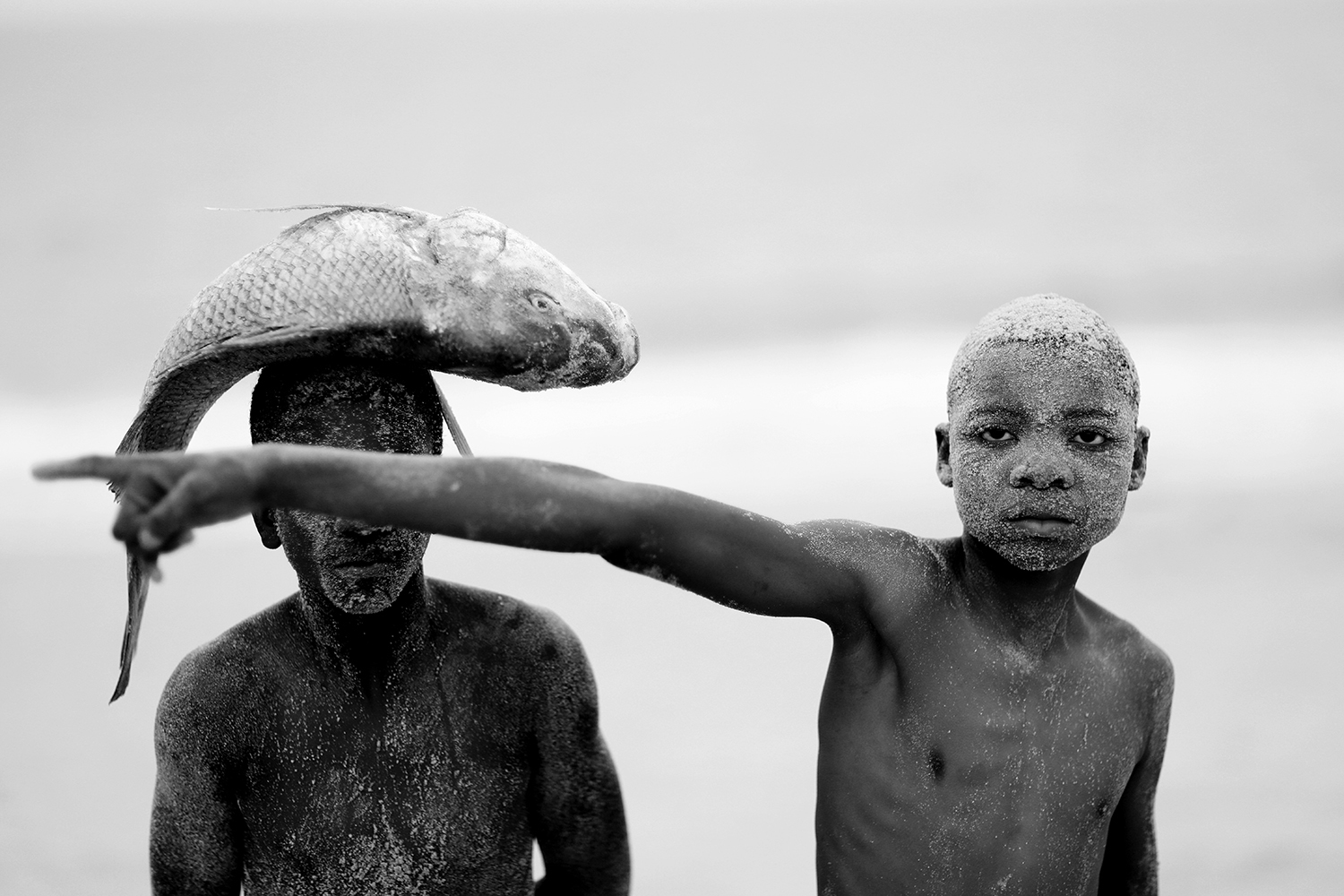 Black and white photography portrait by Mário Macilau, two young boys with fish