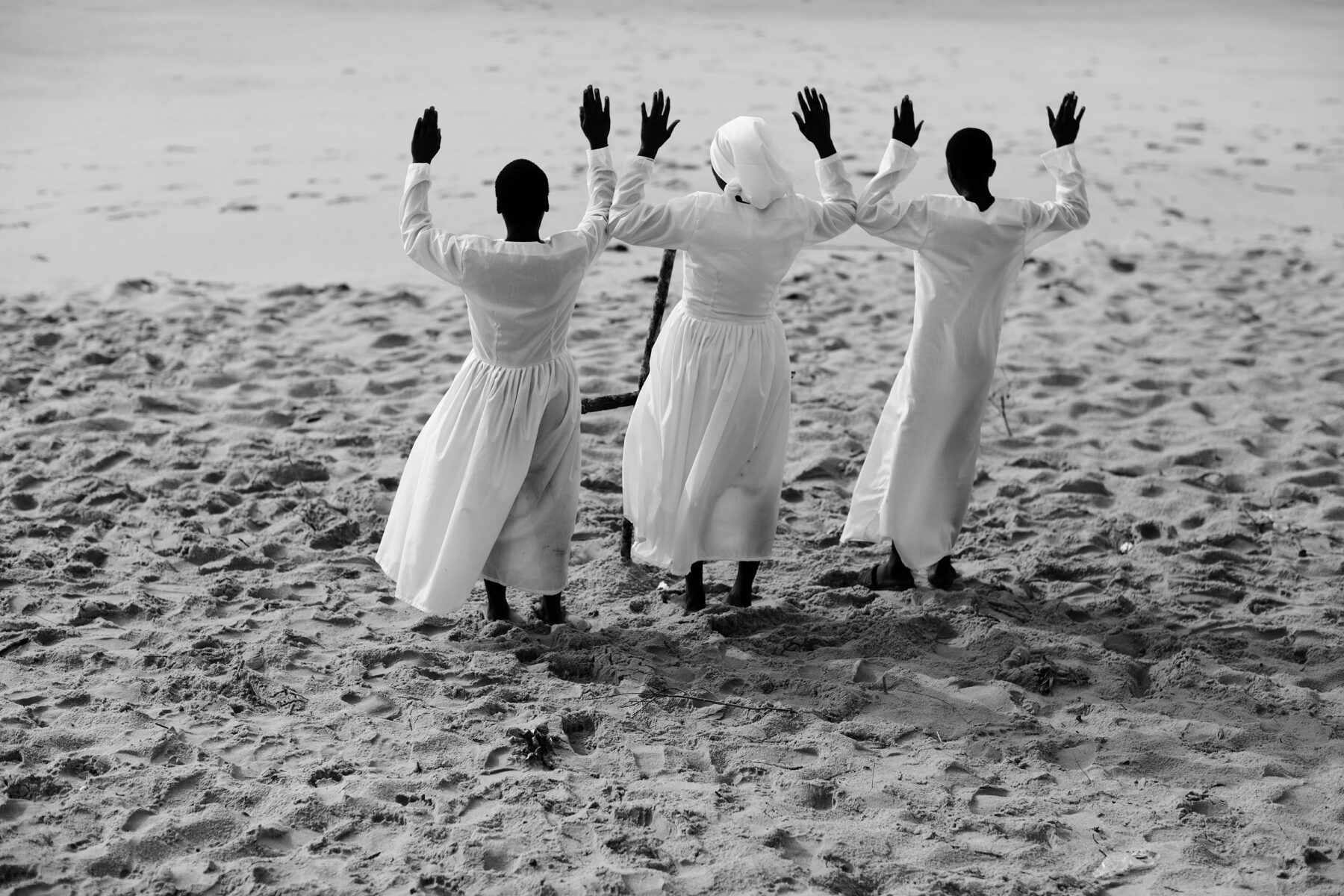 Black and white documentary photography by Mário Macilau, woman on beach performing ritual