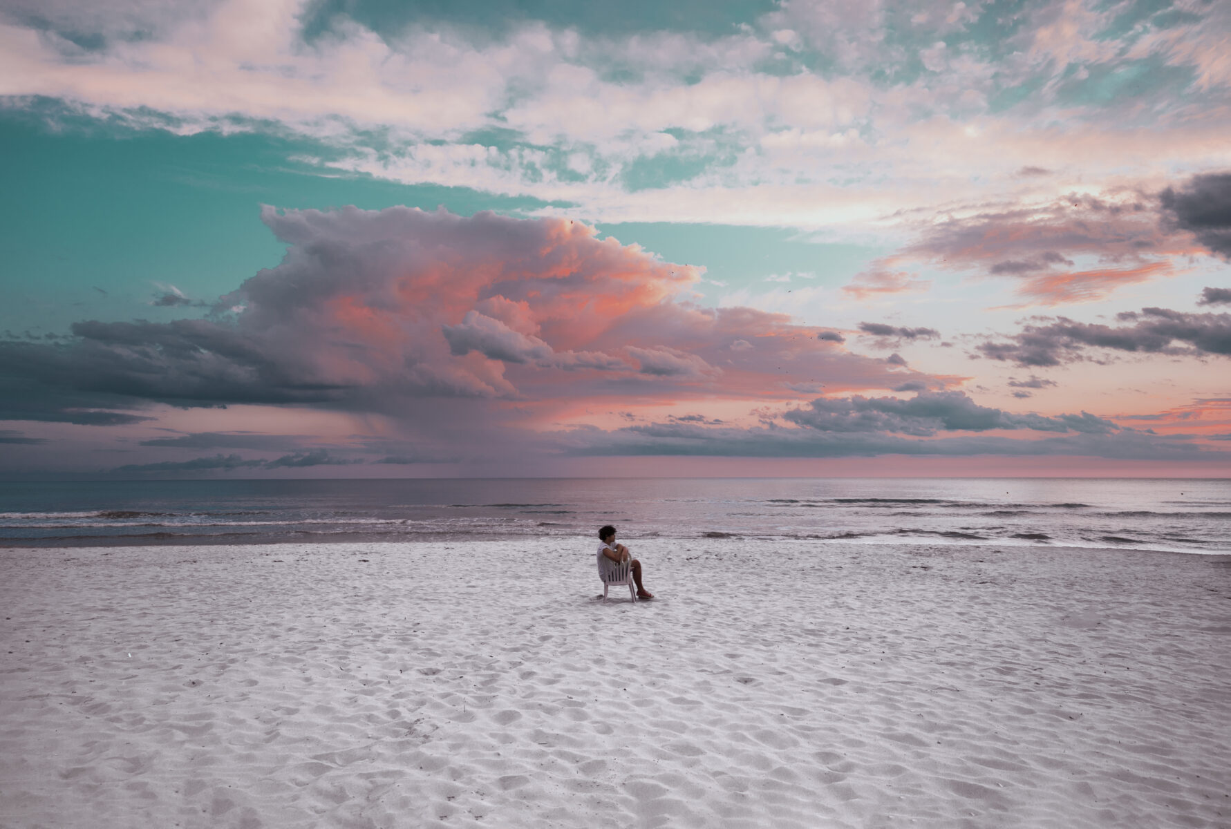 Color photography by Paolo Baretta. Portrait of man on chair, beach, sunset, sunrise, pink sky