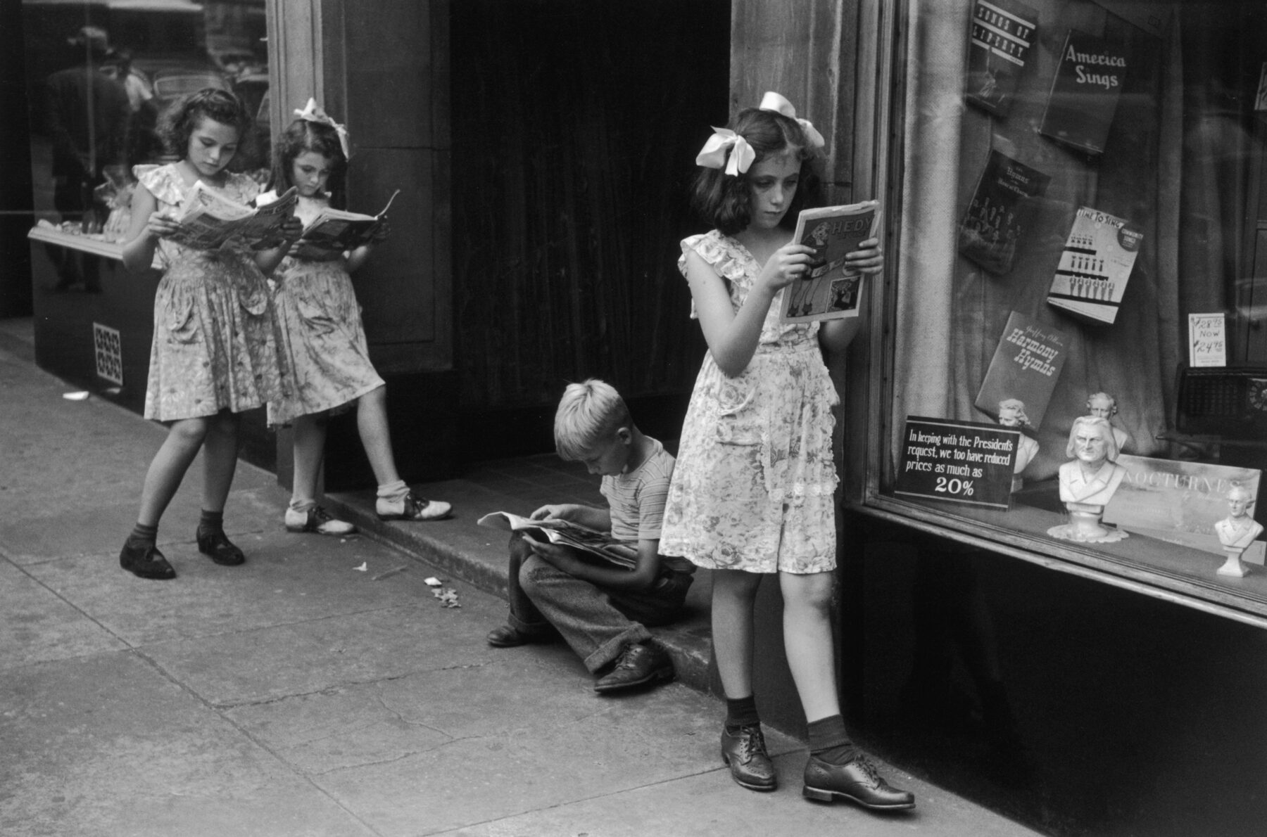 Street photography by Ruth Orkin, Four children, three girls and one boy, loiter on a sidewalk by a store display window while reading comic books, New York City, 1947 (Photo by Ruth Orkin/Hulton Archive/Getty Images)