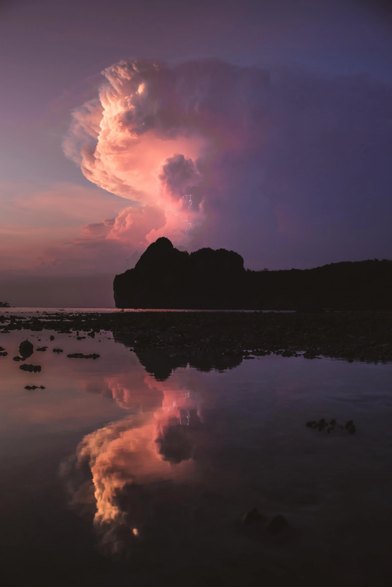 color landscape photo of pink cloud and lightbolts on a coastline by Bennet Witte