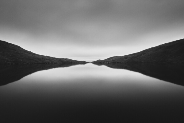 Black and white landscape photography of lake, mountain and sky by Arturs Strikis