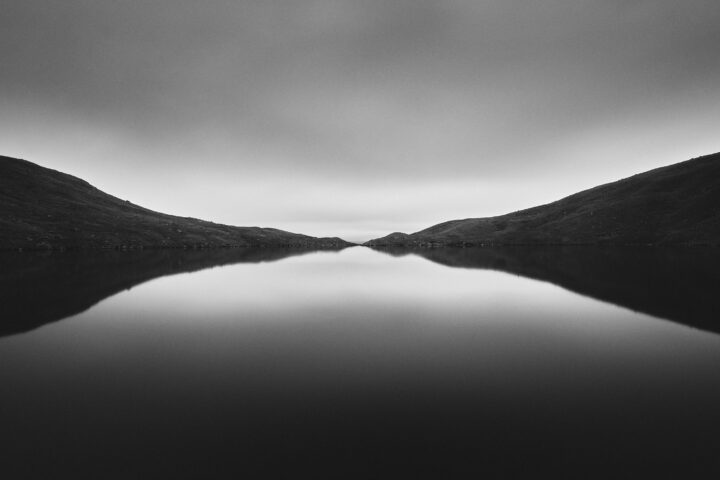 Black and white landscape photography of lake, mountain and sky by Arturs Strikis