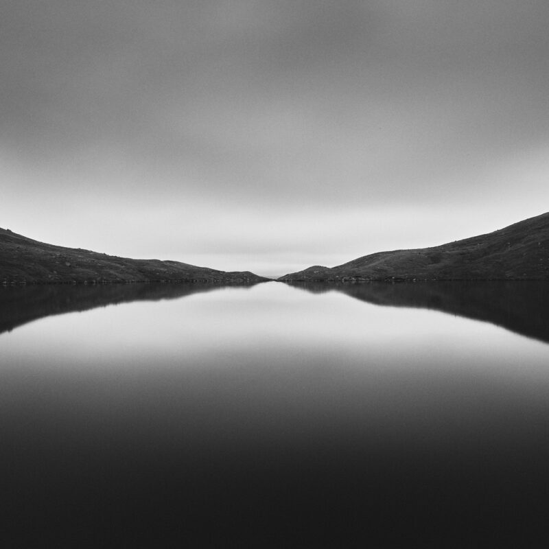 Black and white landscape photography of lake, mountain and sky by Arturs Strikis