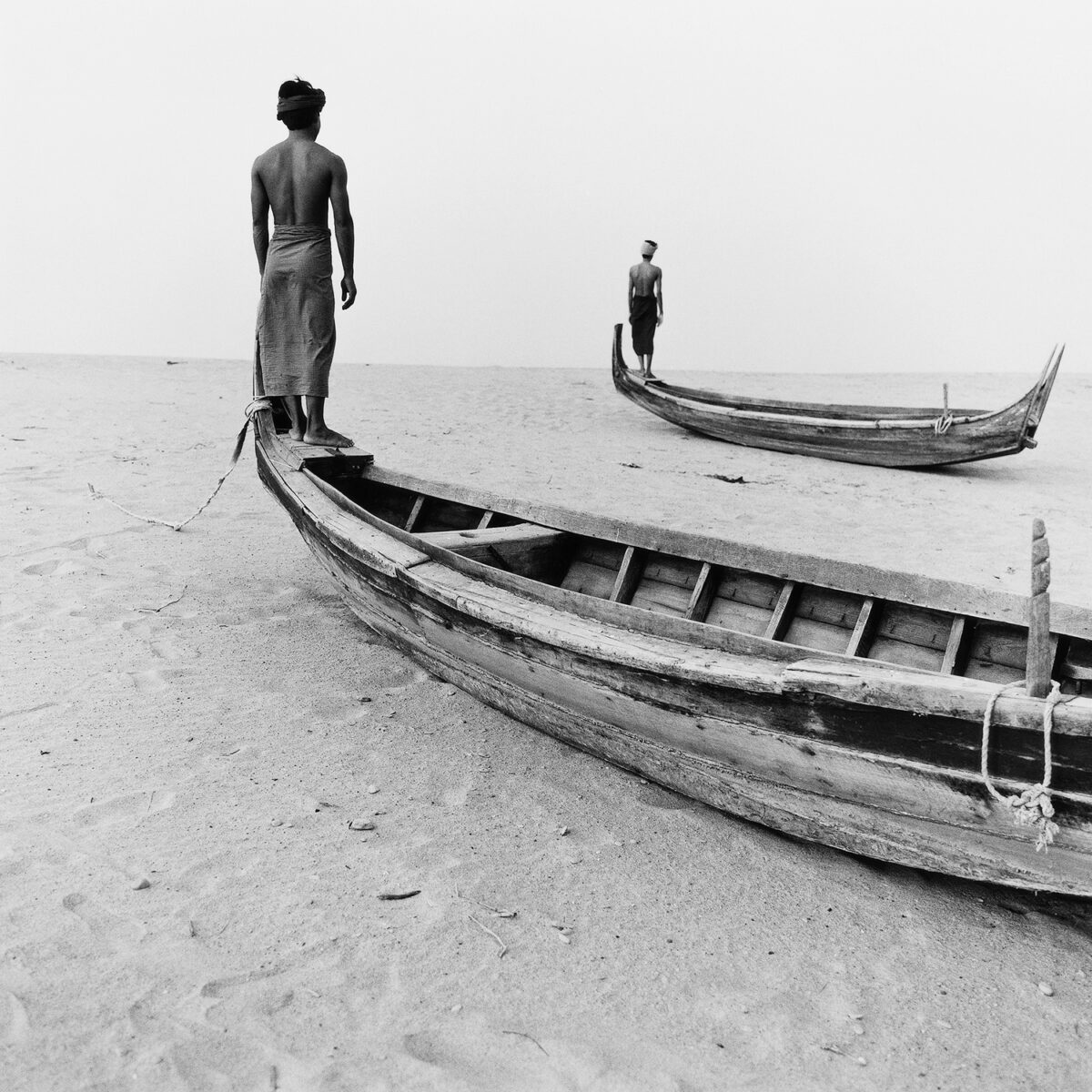 Black & white portrait photography by Monica Denevan, men standing on boats near lake, Burma, Myanmar