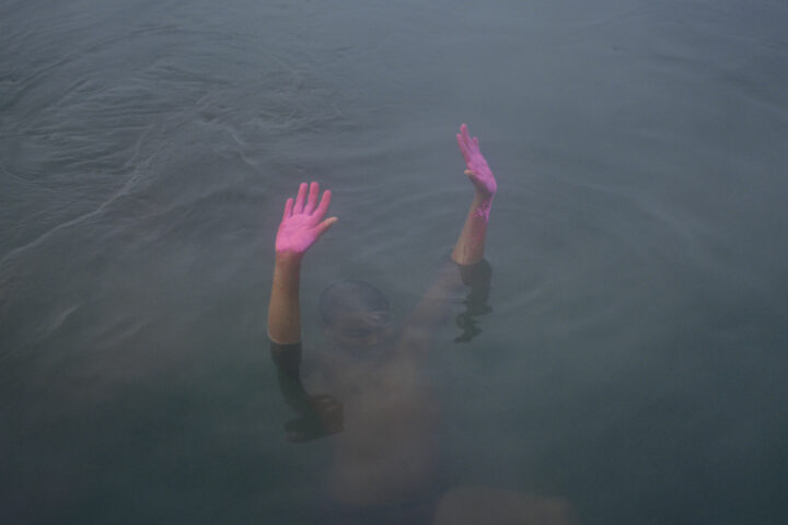 Color photo of boy with pink hands in water by Kin Coedel