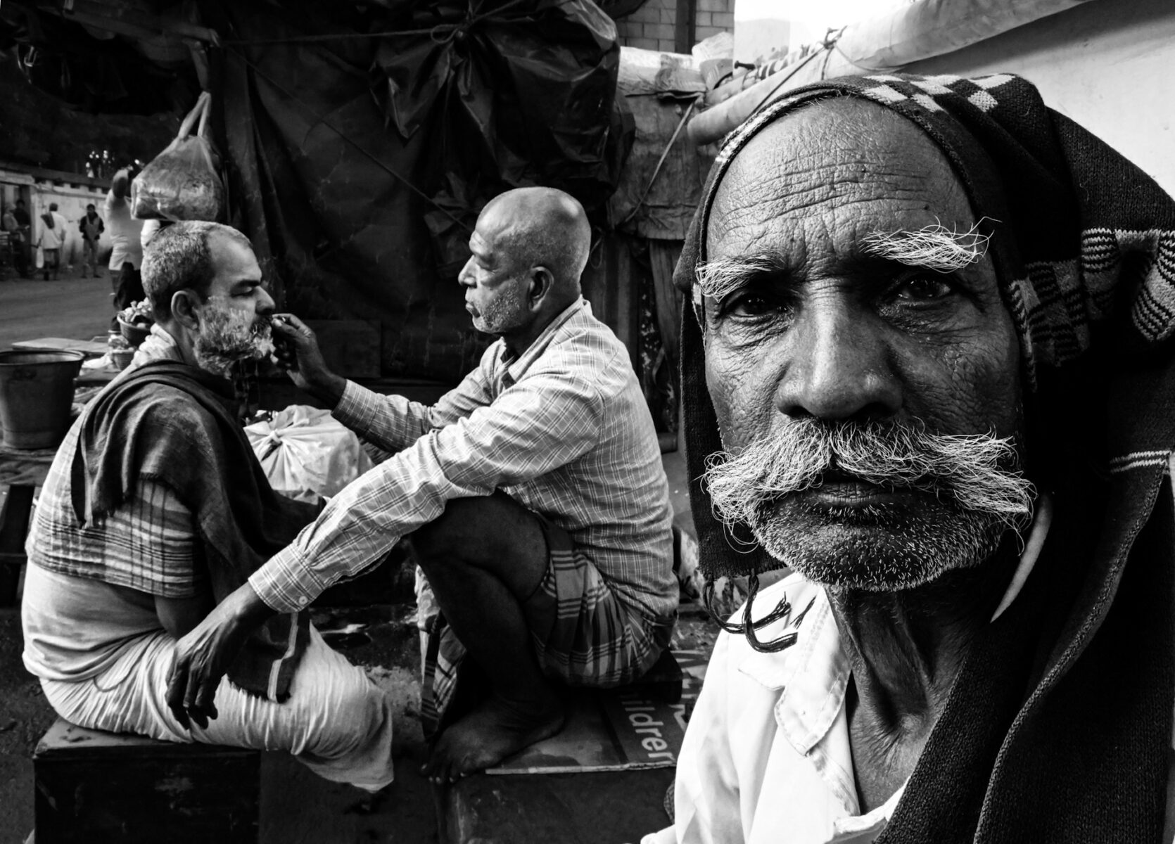 black and white street photo of men shaving in kolkota, india, by Arpit Mehrotra